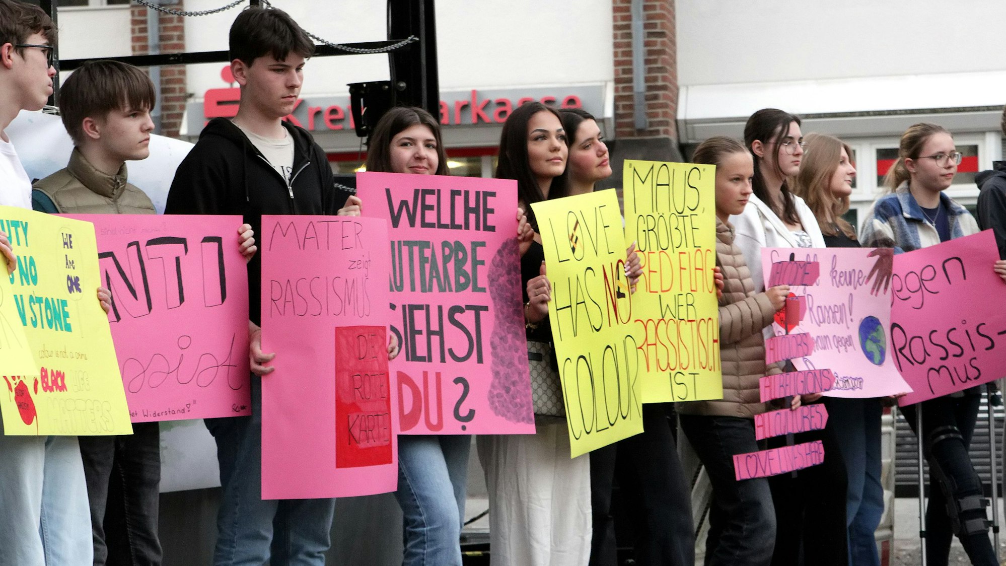 Auf dem Bild sind Schüler zu sehen, die bunte Plakate hoch halten.