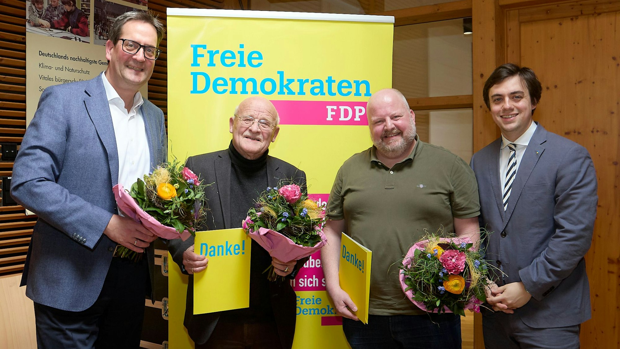 Die vier Männer stehen vor einem Roll-up-Banner der FDP.