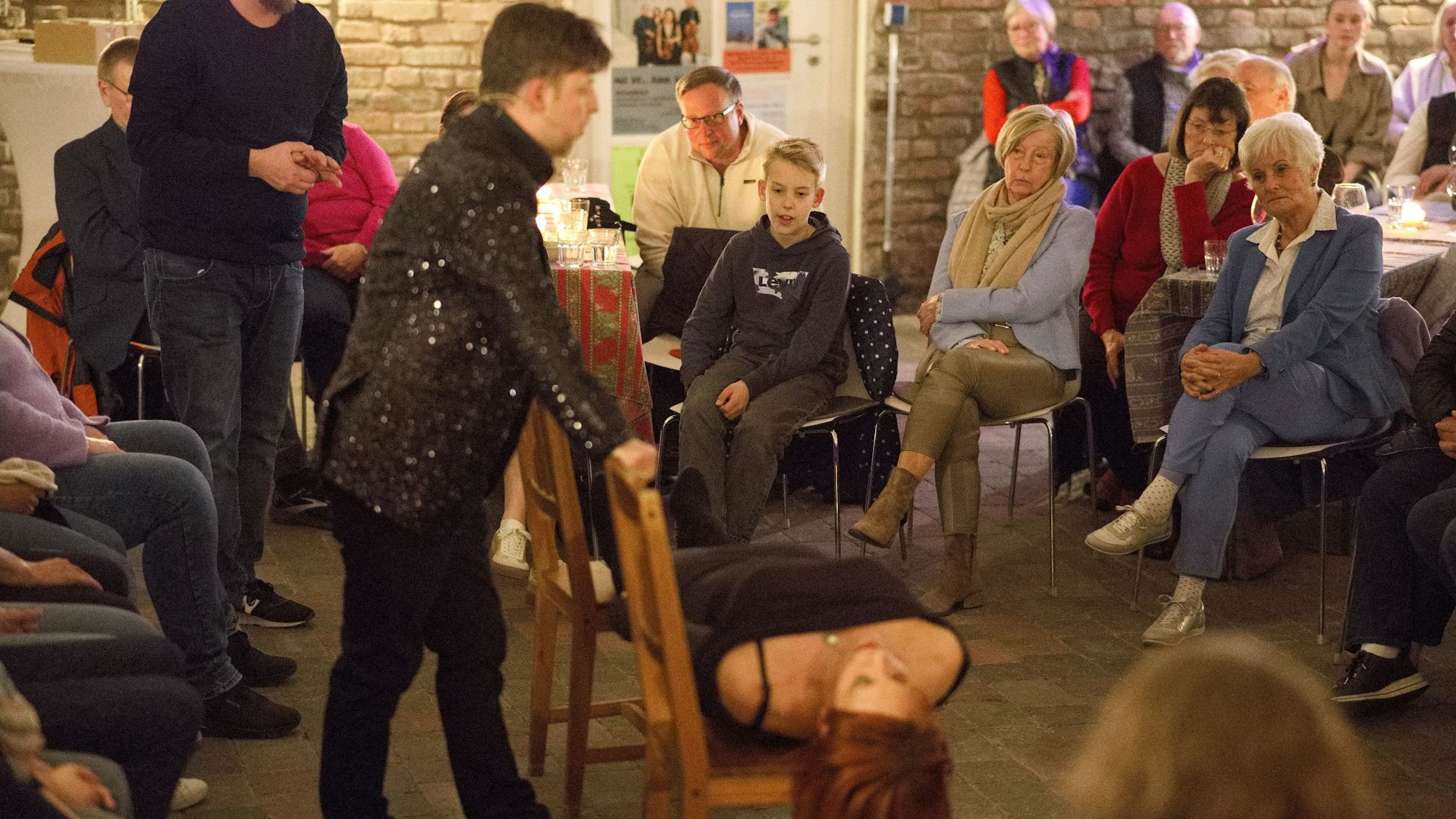 Gebannt schaut das Publikum, wie der Magier Carsten Fenner seine Frau und Assistentin in Trance über zwei Stühle legt.