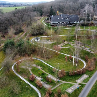 Die Erlebniswelt Eifeltor mit Sommerrodelbahn, Hotel- und Gastronomiegebäuden in Mechernich-Kommern (Drohnenaufnahme).