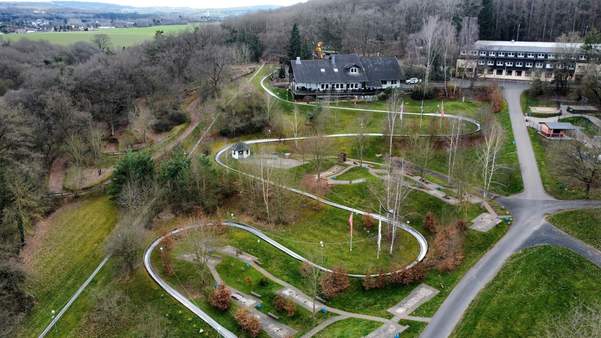 Die Erlebniswelt Eifeltor mit Sommerrodelbahn, Hotel- und Gastronomiegebäuden in Mechernich-Kommern (Drohnenaufnahme).
