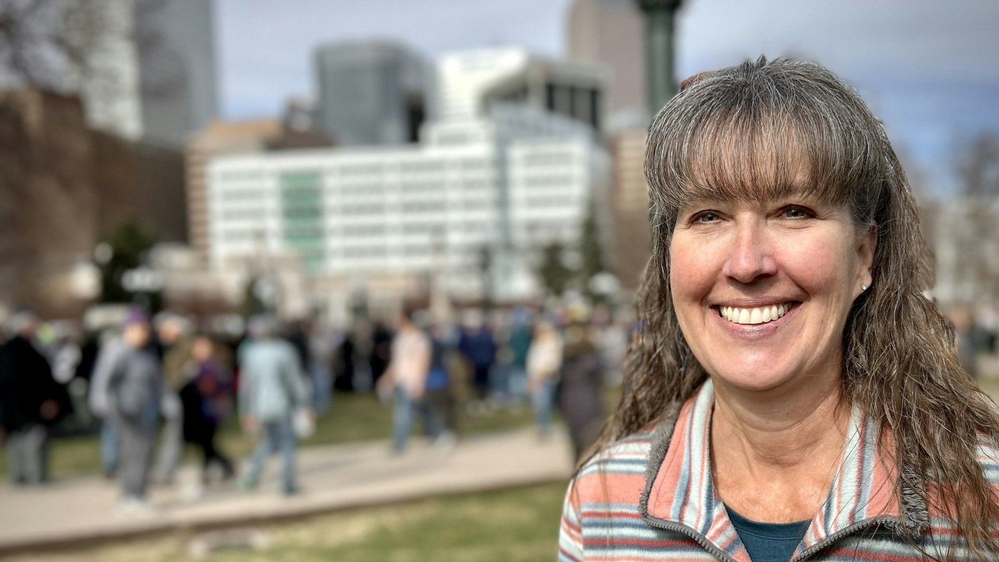 Eine Besucherin der Kundgebung steht vor der sich auflösenden Menschenmenge.