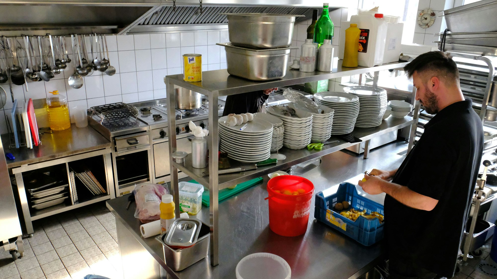 Die Küche im Gastronomie-Gebäude der Erlebniswelt Eifeltor in Mechernich-Kommern. Zwei Mitarbeiter putzen Gemüse.