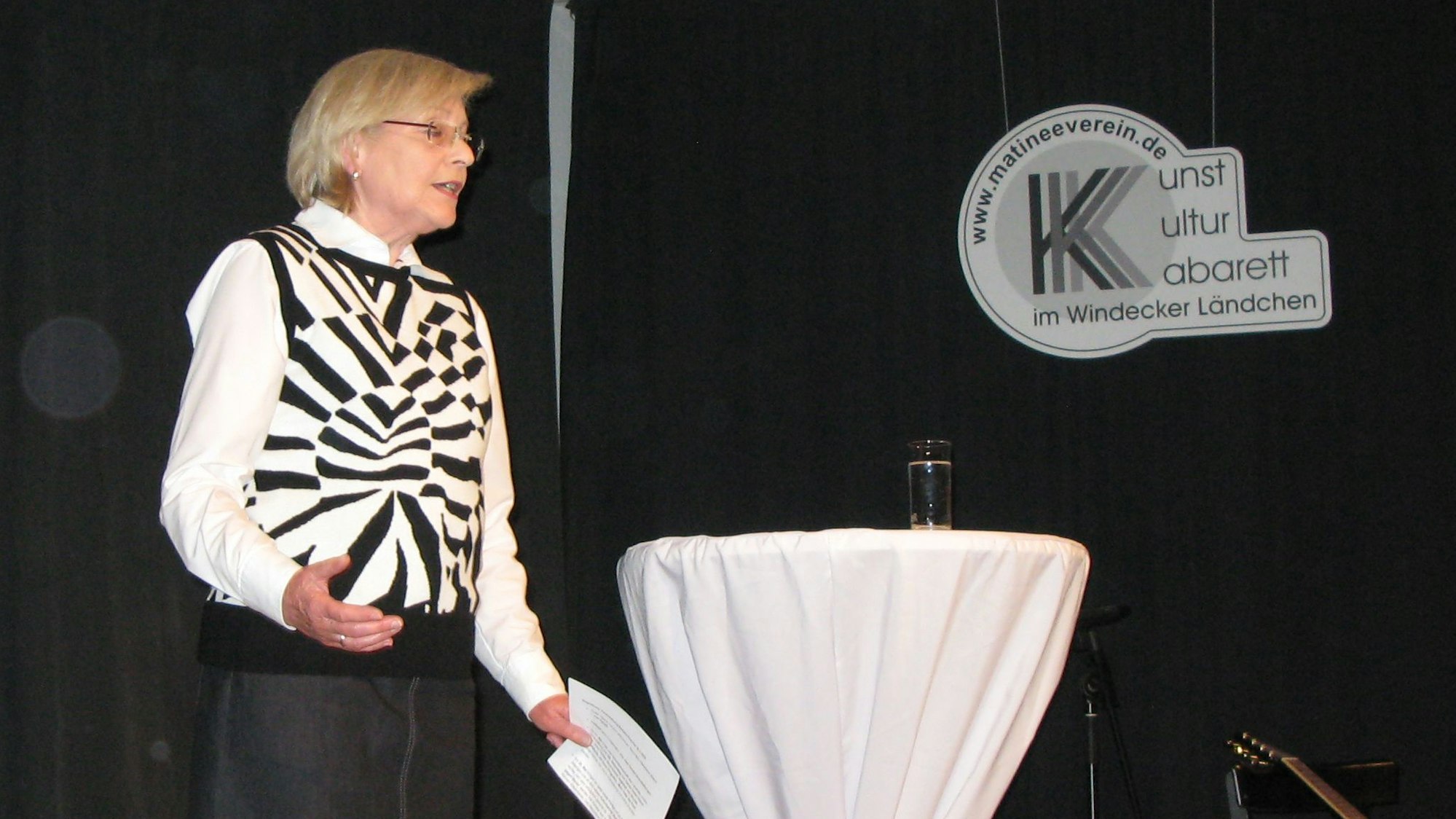 Eine Frau steht auf einer Bühne und spricht.