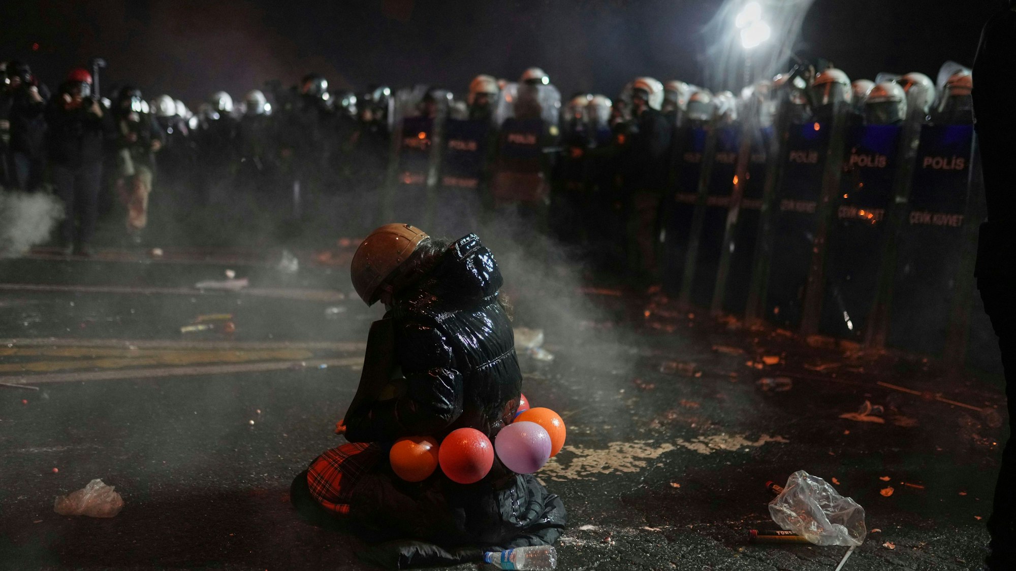 Bei Protesten in Istanbul gegen die Verhaftung Ekrem Imamoglus kniet eine Demonstrantin vor Bereitschaftspolizisten auf der Straße.