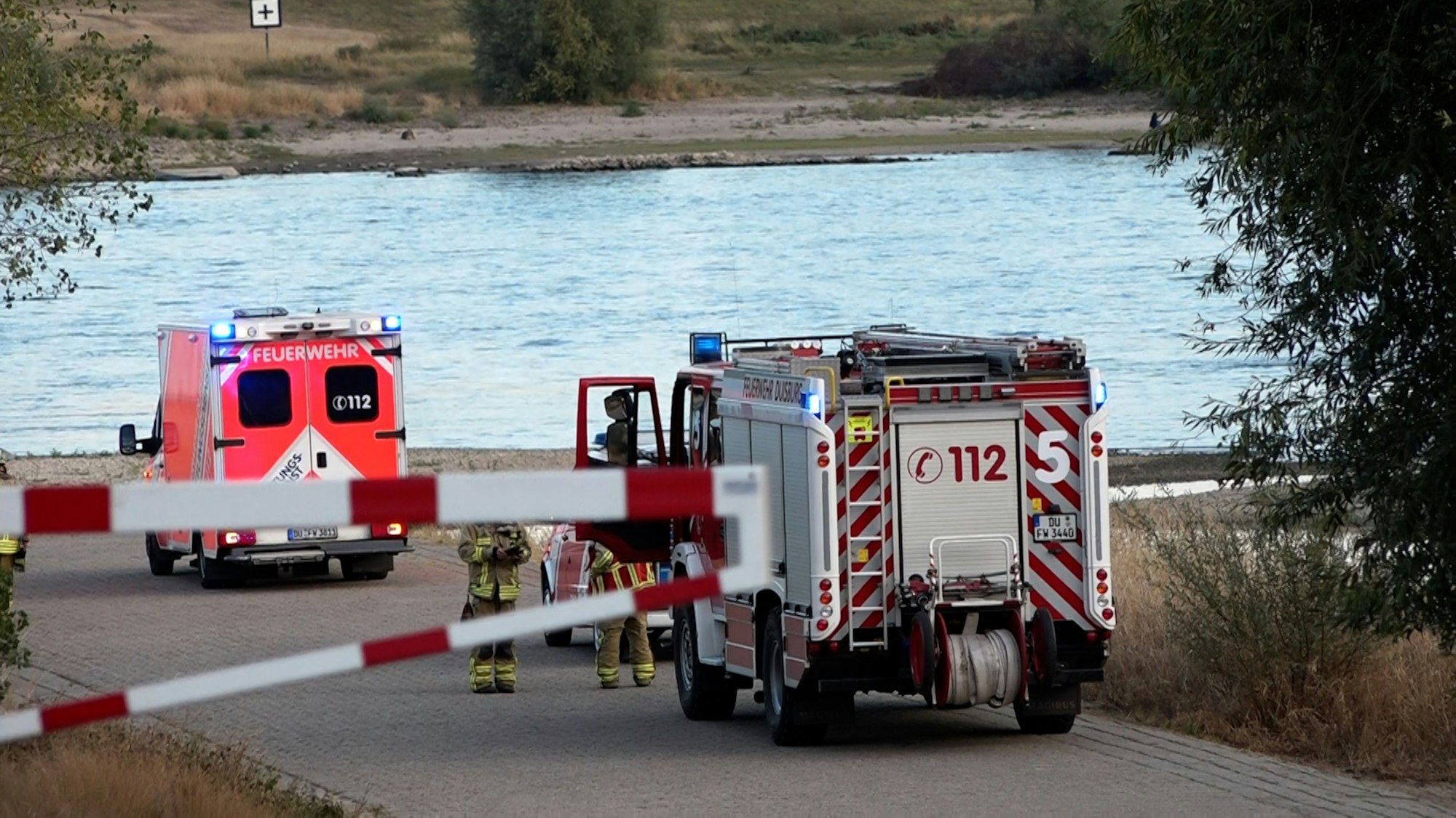 Fahrzeuge der Feuerwehr stehen am Rhein. Die Wasserschutzpolizei in Duisburg will am Mittwoch die Suche nach einem neunjährigen Jungen und seinem 64-jährigen Vater fortsetzen. (zu dpa: "Vater und Sohn am Rhein vermisst - Suche wird fortgesetzt") +++ dpa-Bildfunk +++