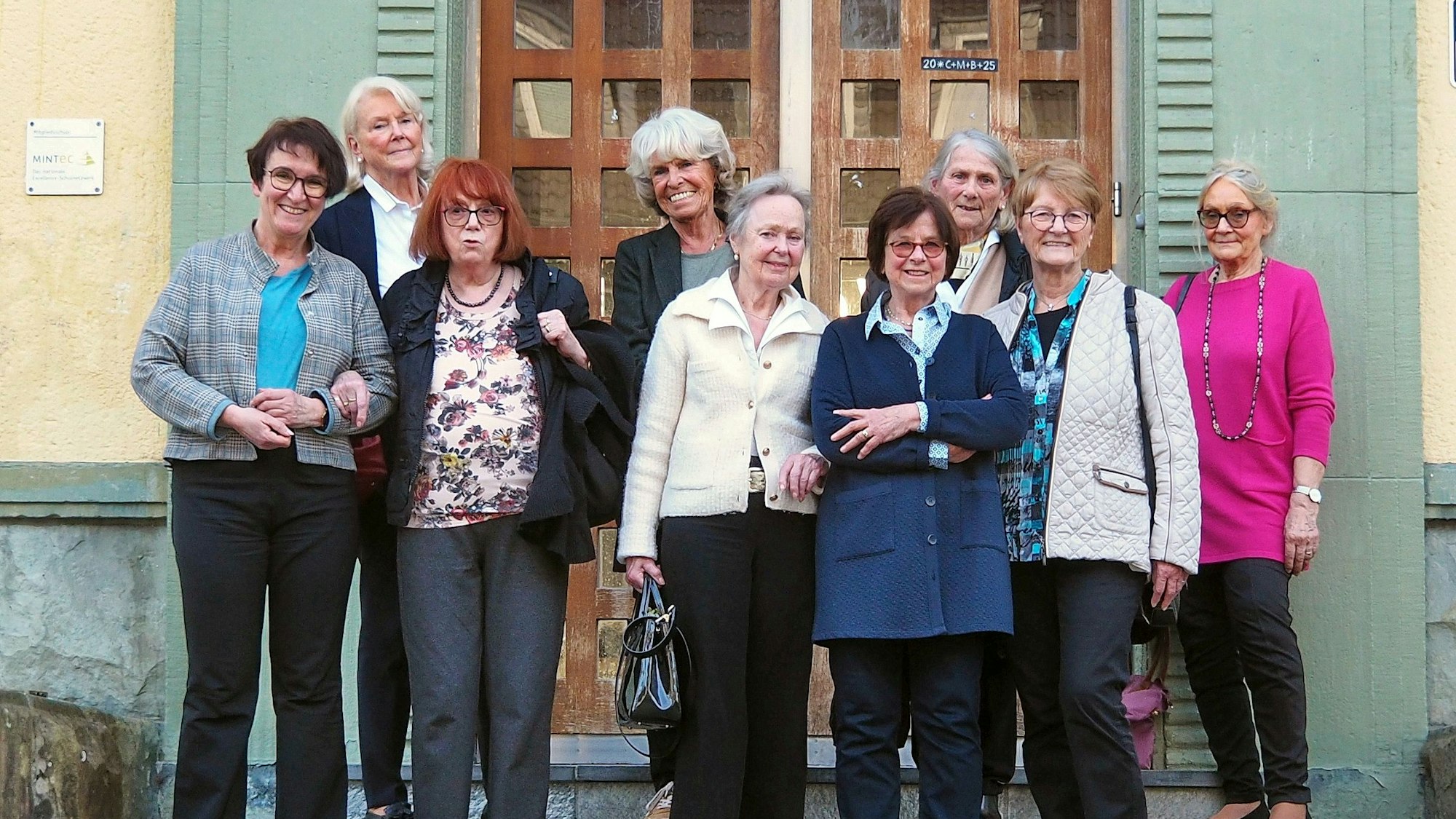 Eine Gruppe älterer Damen steht vor der hölzernen Tür zu einer Kapelle.