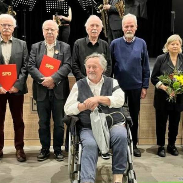 Zu sehen ist Willi Mengel, der im Rollstuhl sitzt. Hinter ihm stehen Parteifreunde.