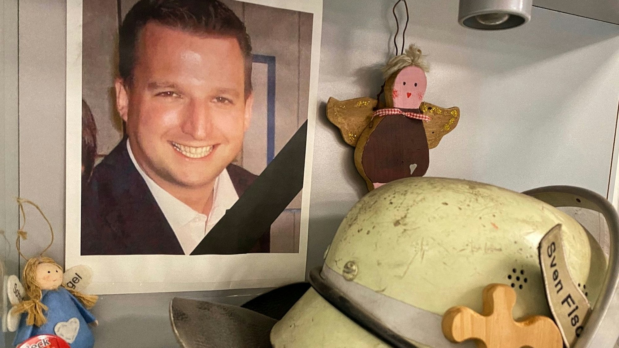 Auf dem Bild ist das Foto des verstorbenen Sven Fischenich zu sehen, zudem Teile seiner Ausrüstung als Feuerwehrmann.