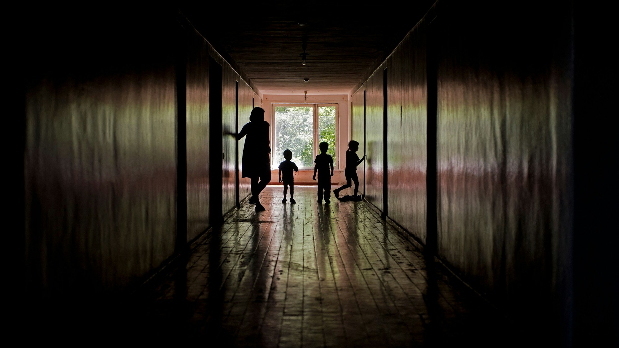 Eine Frau steht mit drei Kindern in einem Flur in einer Zufluchtsstätte für Minderjährige in der Ukraine. (Archivbild)