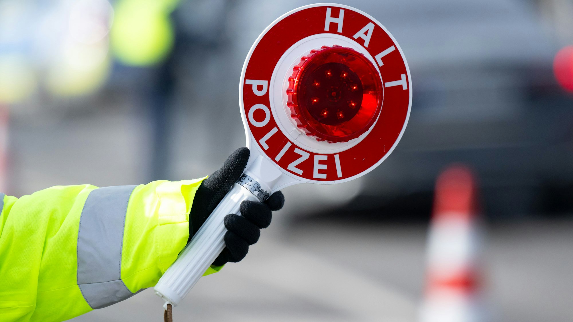 Eine Polizistin hält eine Polizeikelle mit der Aufschrift ·Halt Polizei· in der Hand.