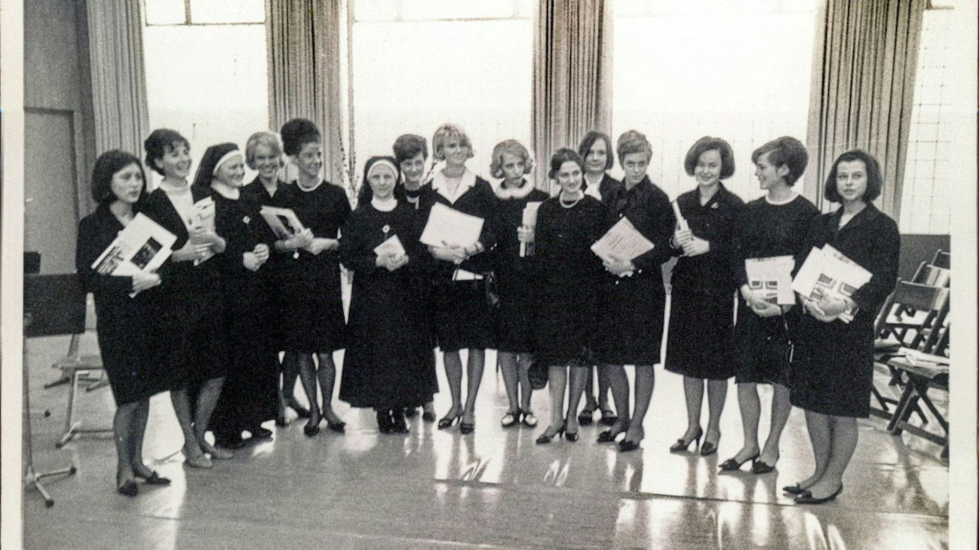 Auf einem Schwarz-Weiß-Foto sind 15 junge Frauen in schwarzen Röcken zu sehen. Dabei stehen auch zwei Nonnen.