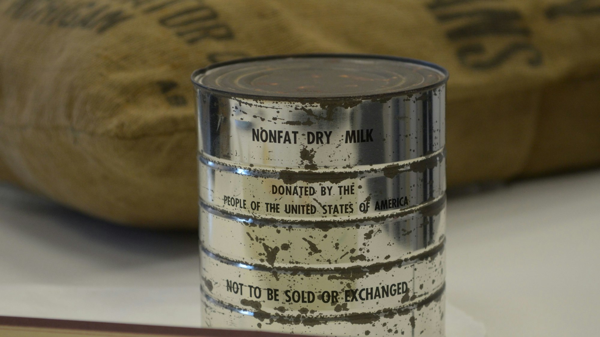Das Foto zeigt eine Dose mit starken Altersspuren. Die Aufschrift am oberen Rand lautet „Nonfat Dry Milk“.