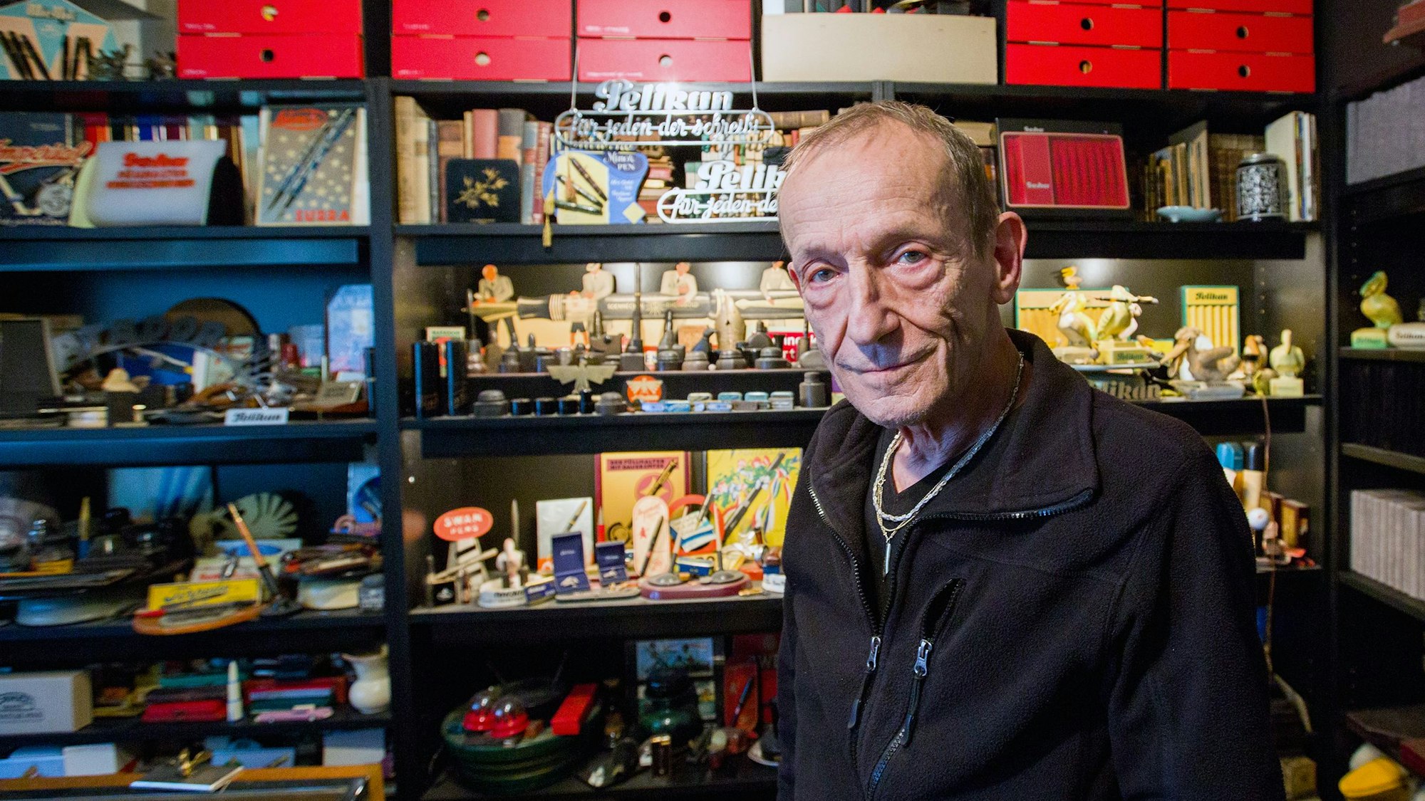 Ein Mann sitzt vor einem Regal, in dem diverses Füllfeder-Zubehör zu sehen ist.