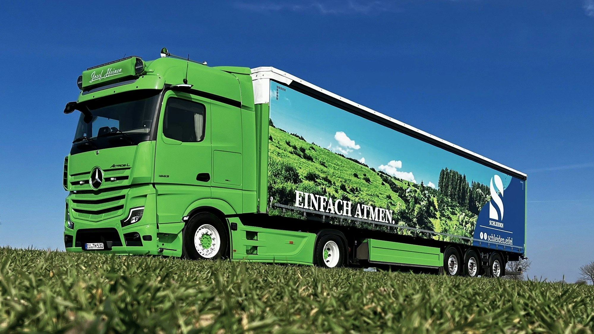 Blick auf den Lkw mit dem Foto einer Eifellandschaft und dem Schriftzug „Einfach atmen“.