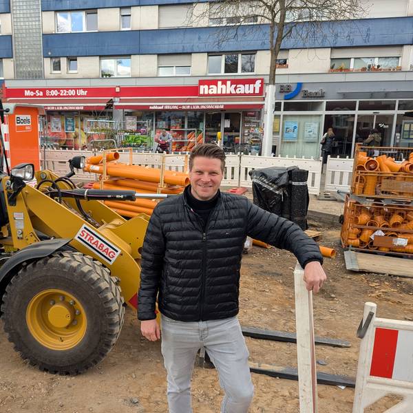 Das Foto zeigt den Nahkauf-Inhaber vor einem Radlader auf der Baustelle vor seinem Geschäft.