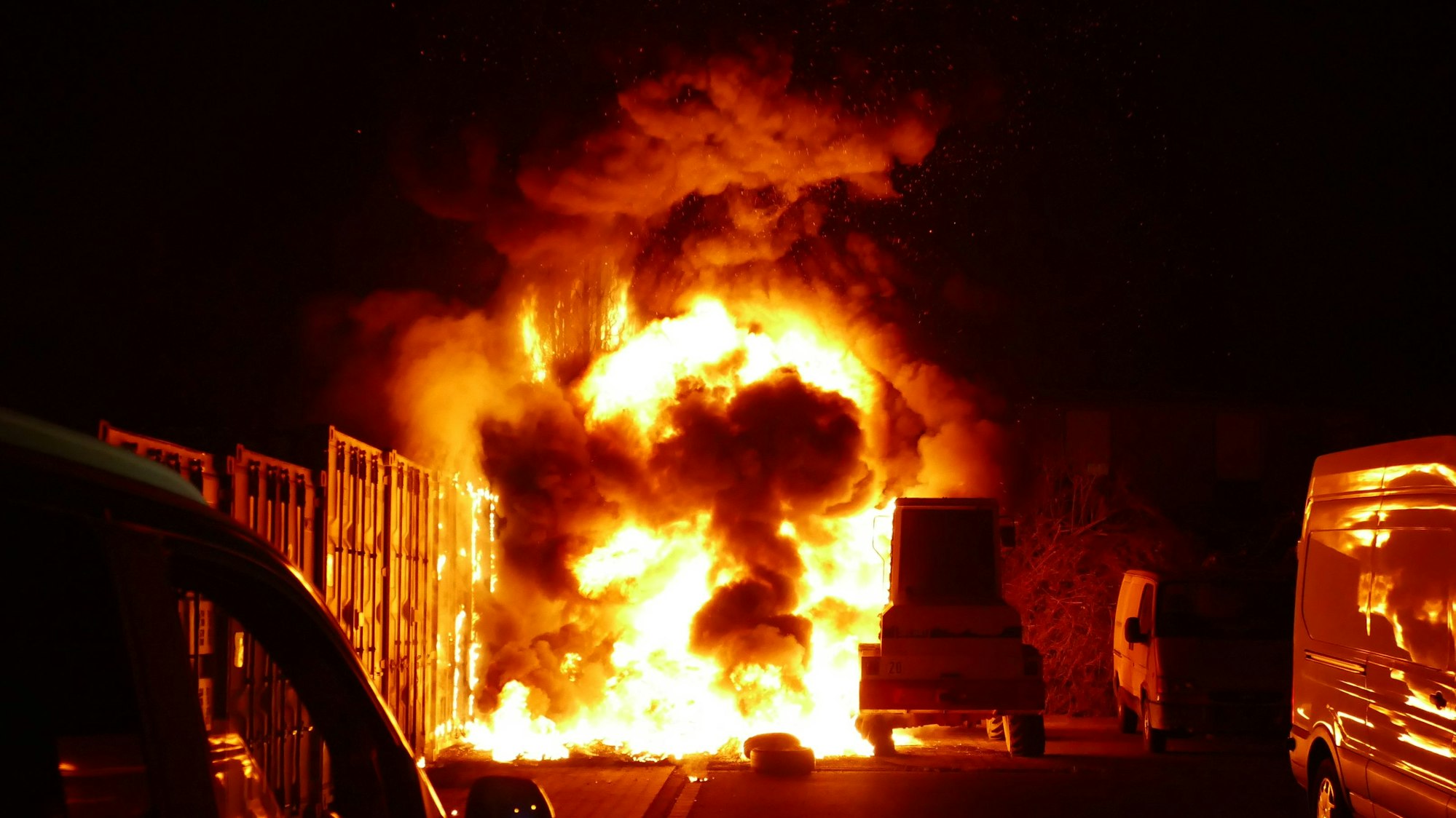 Ein brennender Reifenstapel neben einem Radlader.