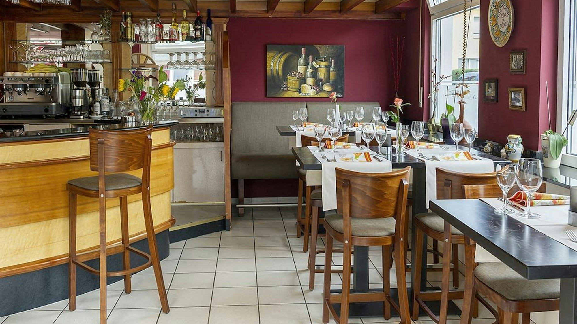 Blick in ein Lokal mit Theke, Tischen und weiß-gefliestem Boden.