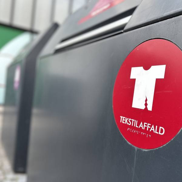 Eine Mülltonne für Textilabfall steht in Kopenhagen vor einem Einkaufszentrum.