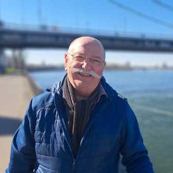 Ein Mann steht vor einer Brücke am Rhein