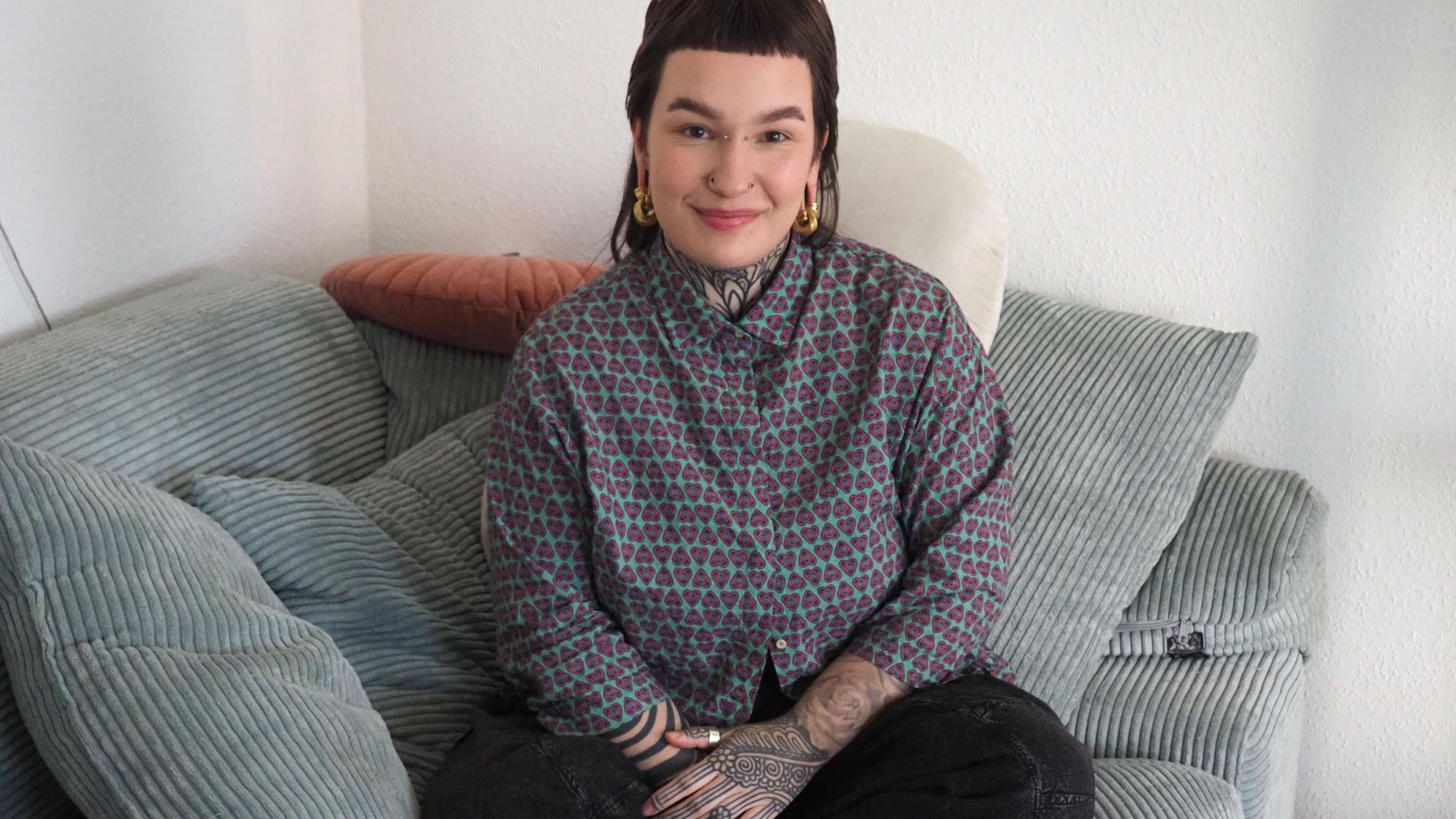 Laura Gertz sitzt im Schneidersitz auf einer Couch.