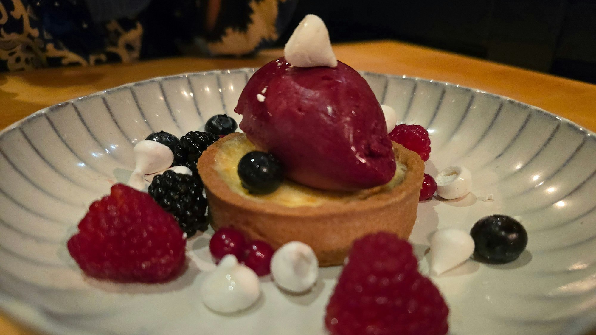 Ein Tartelette mit Beeren garniert und einer Sorbet-Nocke obenauf ist zu sehen.