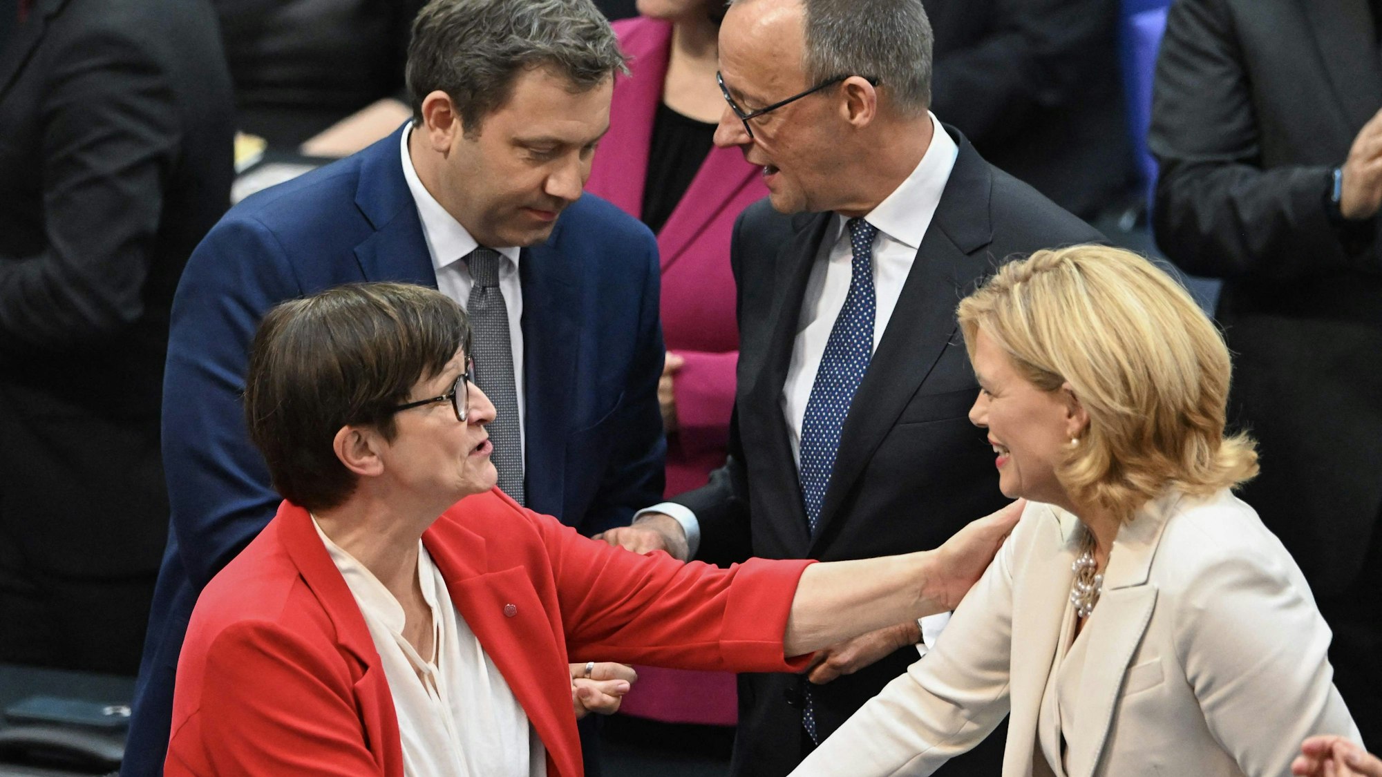 Julia Klöckner (rechts, CDU) erhält Glückwünsche von Saskia Esken (SPD), während sich im Hintergrund Friedrich Merz (rechts, CDU) und Lars Klingbeil (SPD) unterhalten.