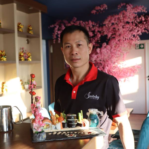 Zu sehen ist Nguyen van Loc, der eine Patte mit Sushi präsentiert.