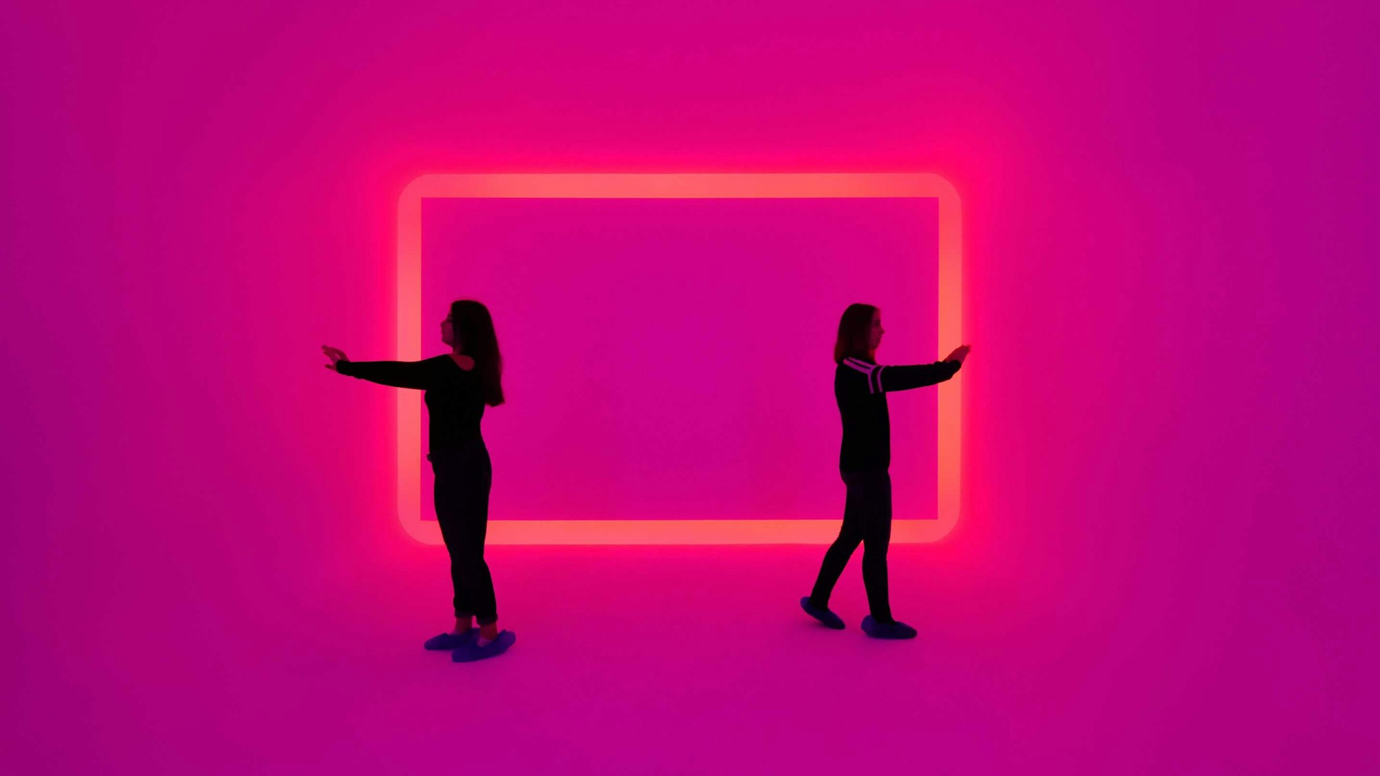 Zwei Frauen stehen in einem Raum, der in pink leuchtet.