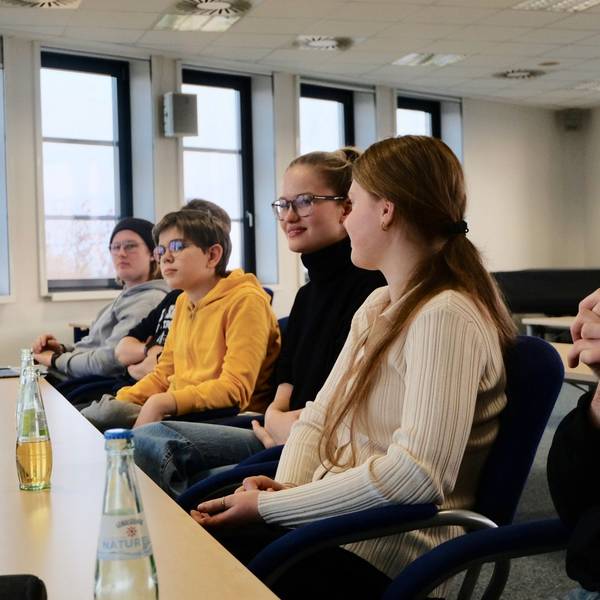 Fünf Schüler und Schülerinnen sitzen mit ihrem Vertrauenslehrer an einem Tisch.