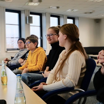 Fünf Schüler und Schülerinnen sitzen mit ihrem Vertrauenslehrer an einem Tisch.