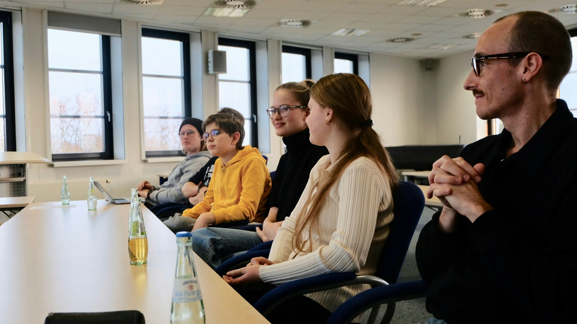 Fünf Schüler und Schülerinnen sitzen mit ihrem Vertrauenslehrer an einem Tisch.