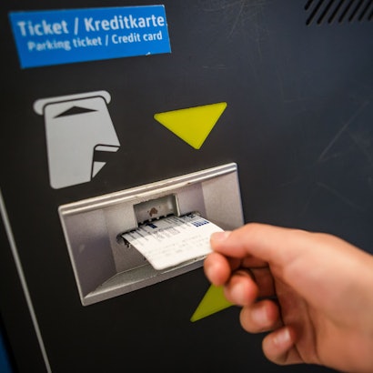 Eine Frau führt in einem Parkhaus in Stuttgart einen Parkschein in einen Automaten ein.