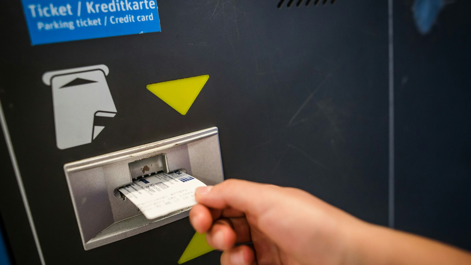 Eine Frau führt in einem Parkhaus in Stuttgart einen Parkschein in einen Automaten ein.