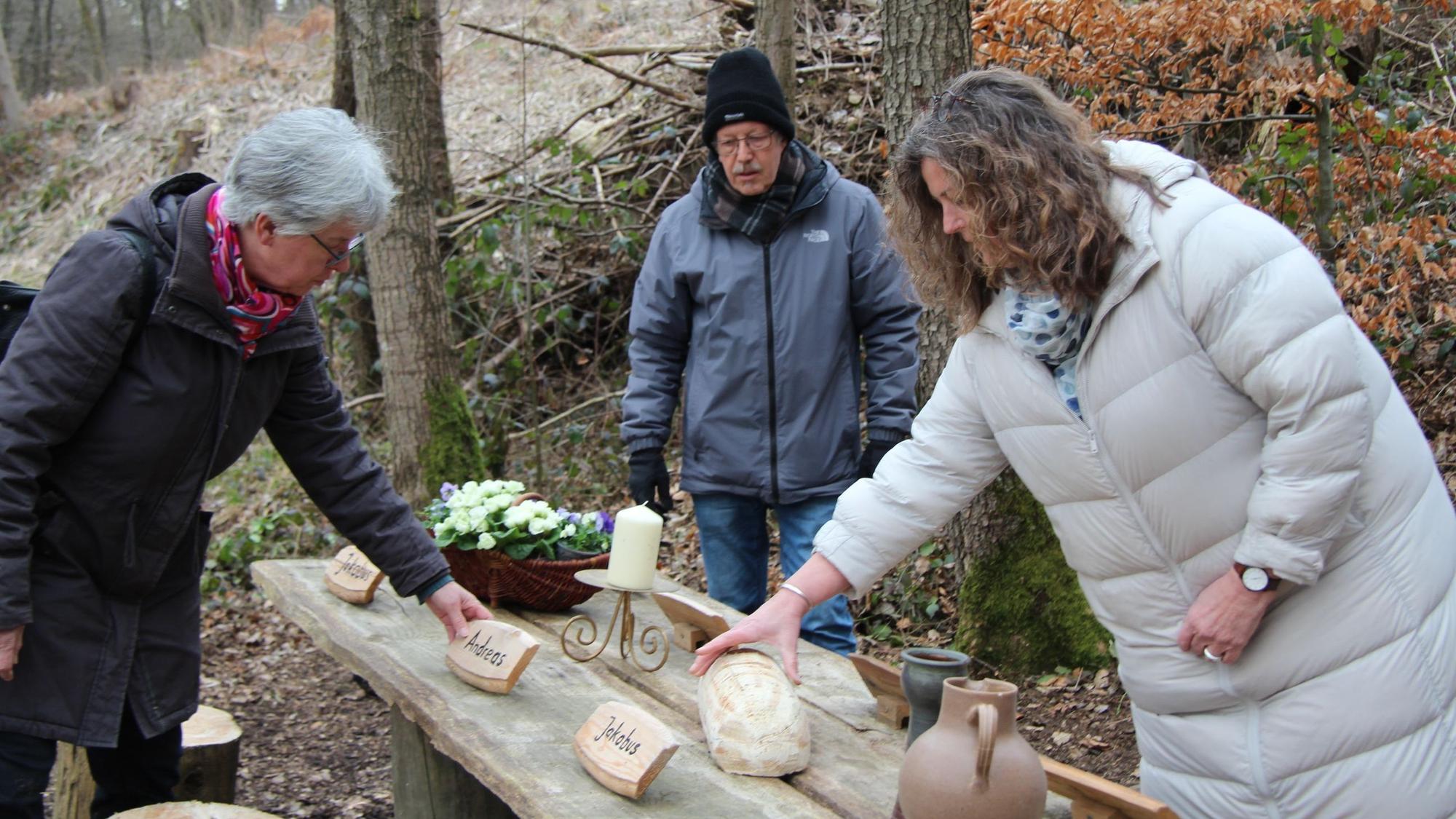 Drei Frauen stellen auf einem Holztisch im Wald das Letzte Abendmahl nach.