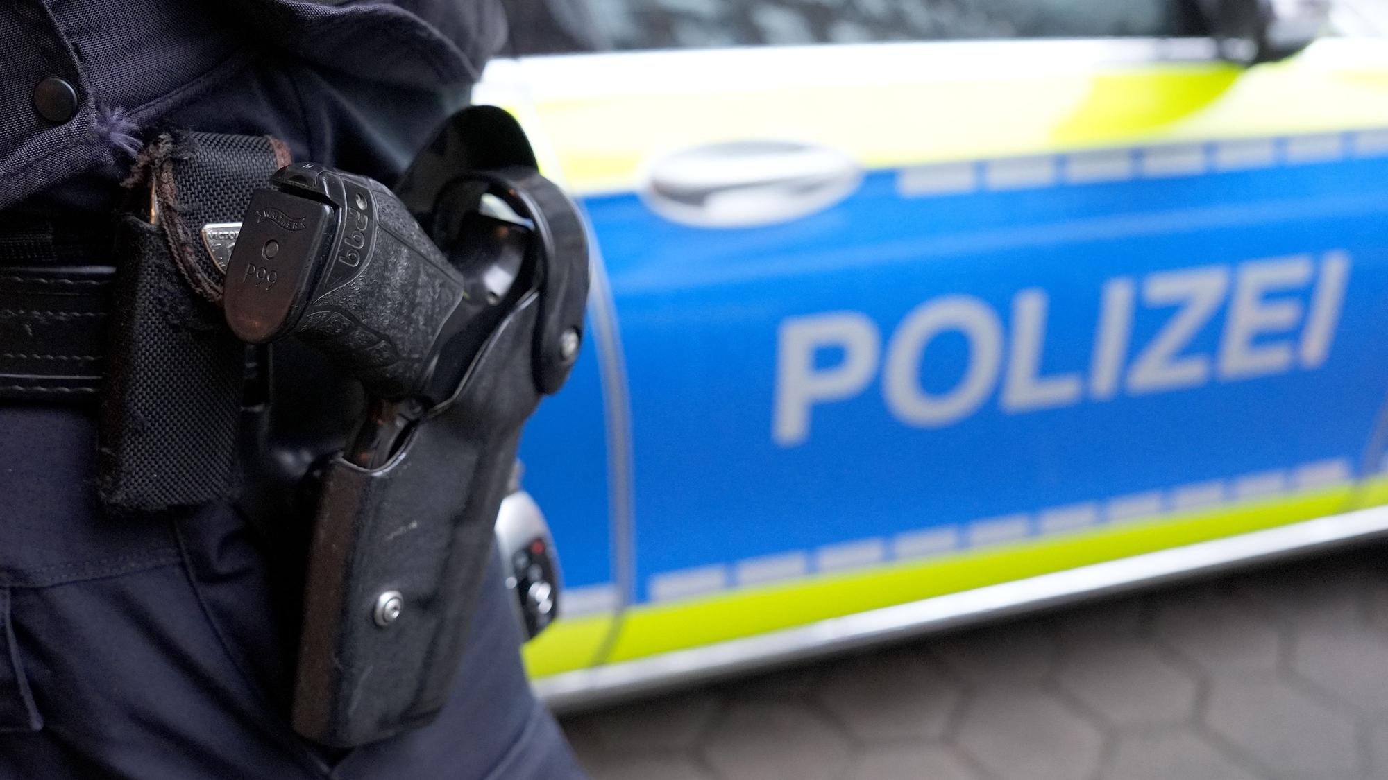 Ein Polizist steht vor einem Einsatzfahrzeug der Polizei.