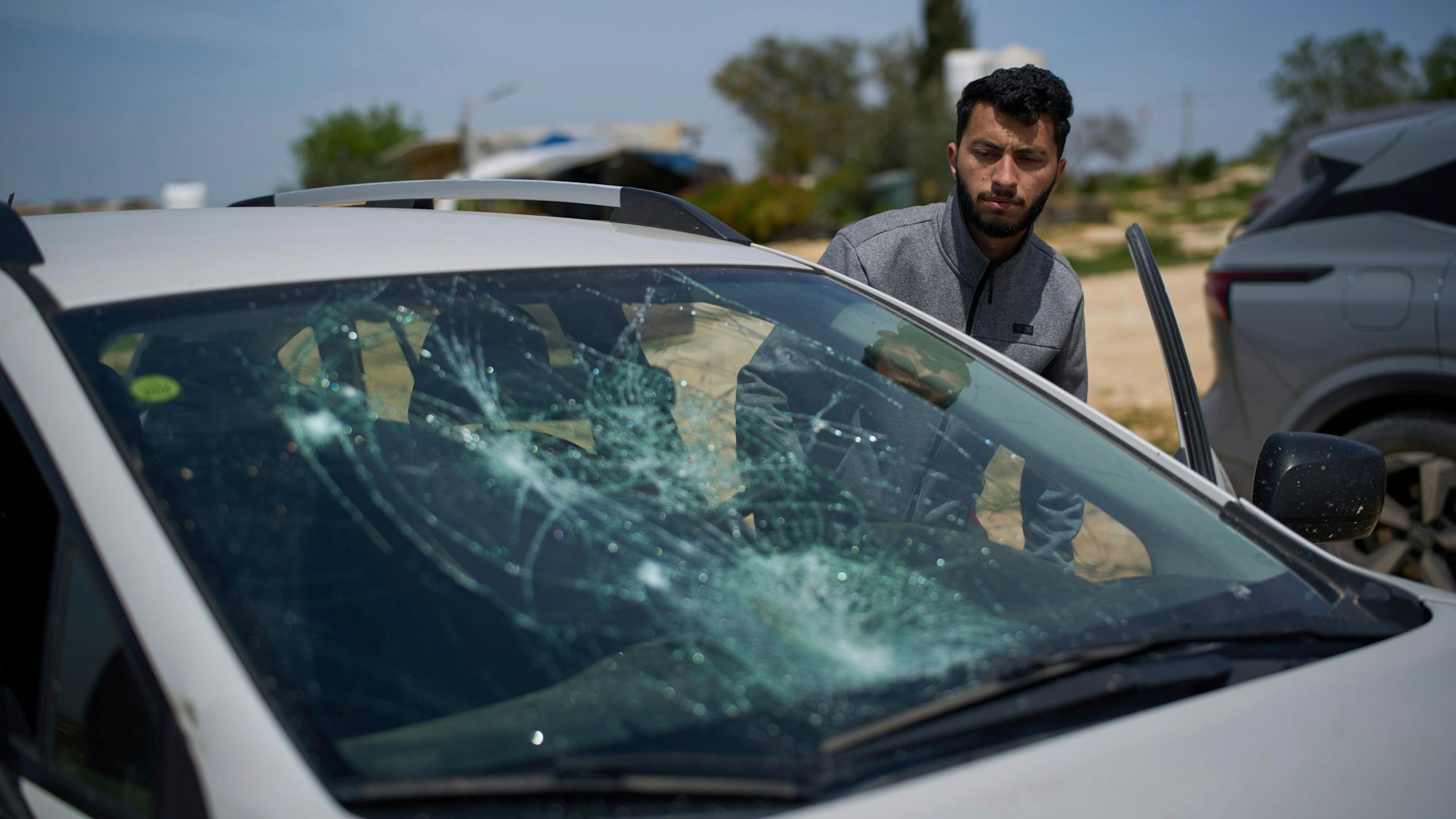 Basel Adra, palästinensischer Co-Regisseur des Oscar-prämierten Dokumentarfilms ‚No Other Land‘, betrachtet ein beschädigtes Auto nach einem Siedlerangriff im Dorf Susiya in Masafer Yatta in den südlichen Hebron-Bergen.