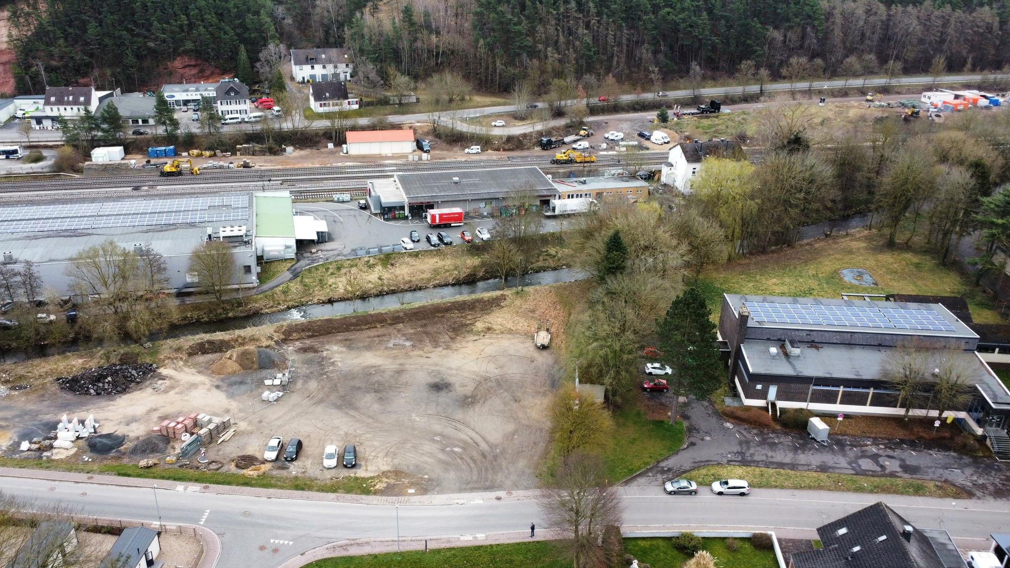 Blick auf den Platz mit Baumaterialien und dem Schwimmbad (Drohnenaufnahme).