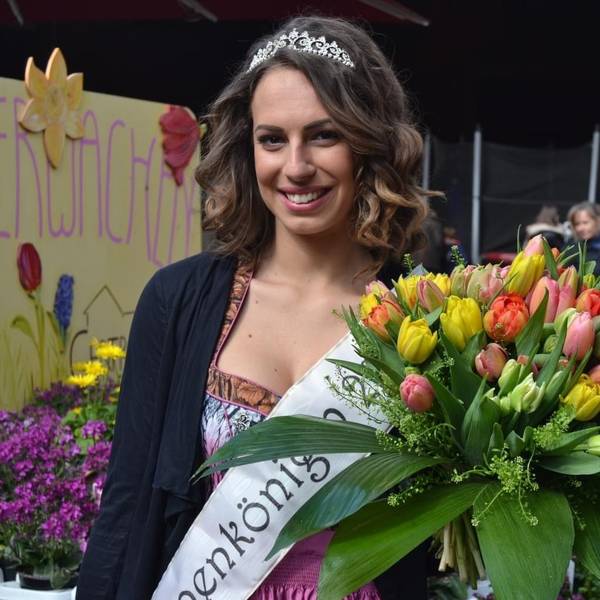 Das Foto zeigt eine Frau mit Schärpe, Krone und einem großen Strauß Tulpen.