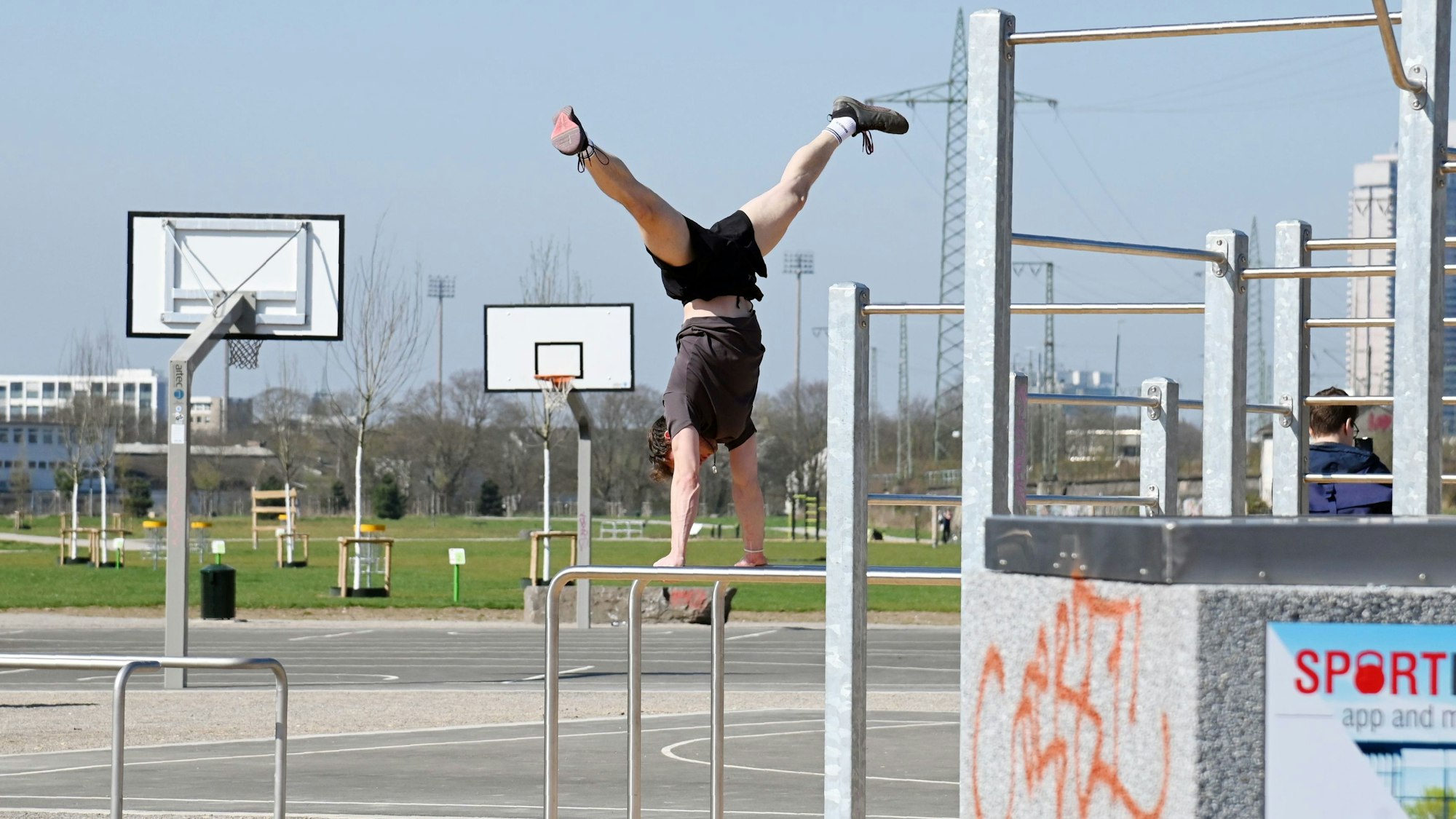 Zu sehen ist ein Mann, der im neuen Sportpionierpark einen Handstand auf einem Klettergerüst macht.