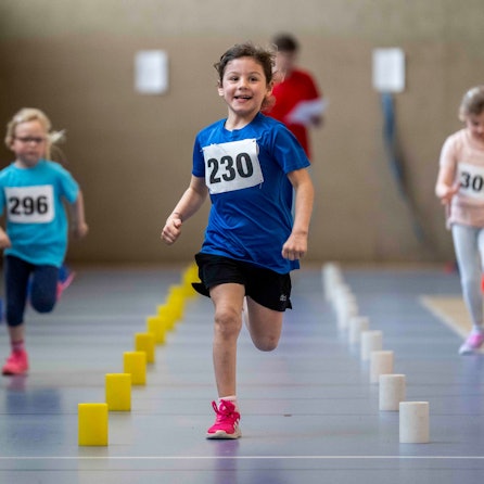 Ein Mädchen, das offenbar in Führung liegt, strahlt während sie läuft.