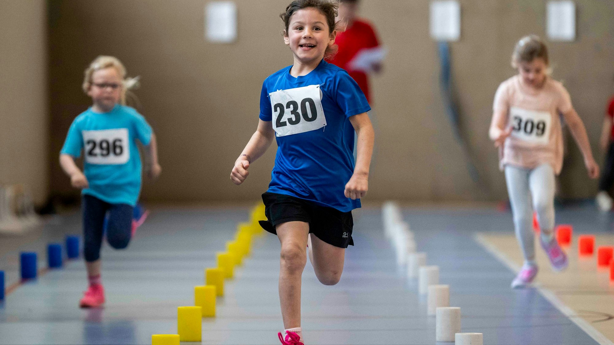 Ein Mädchen, das offenbar in Führung liegt, strahlt während sie läuft.