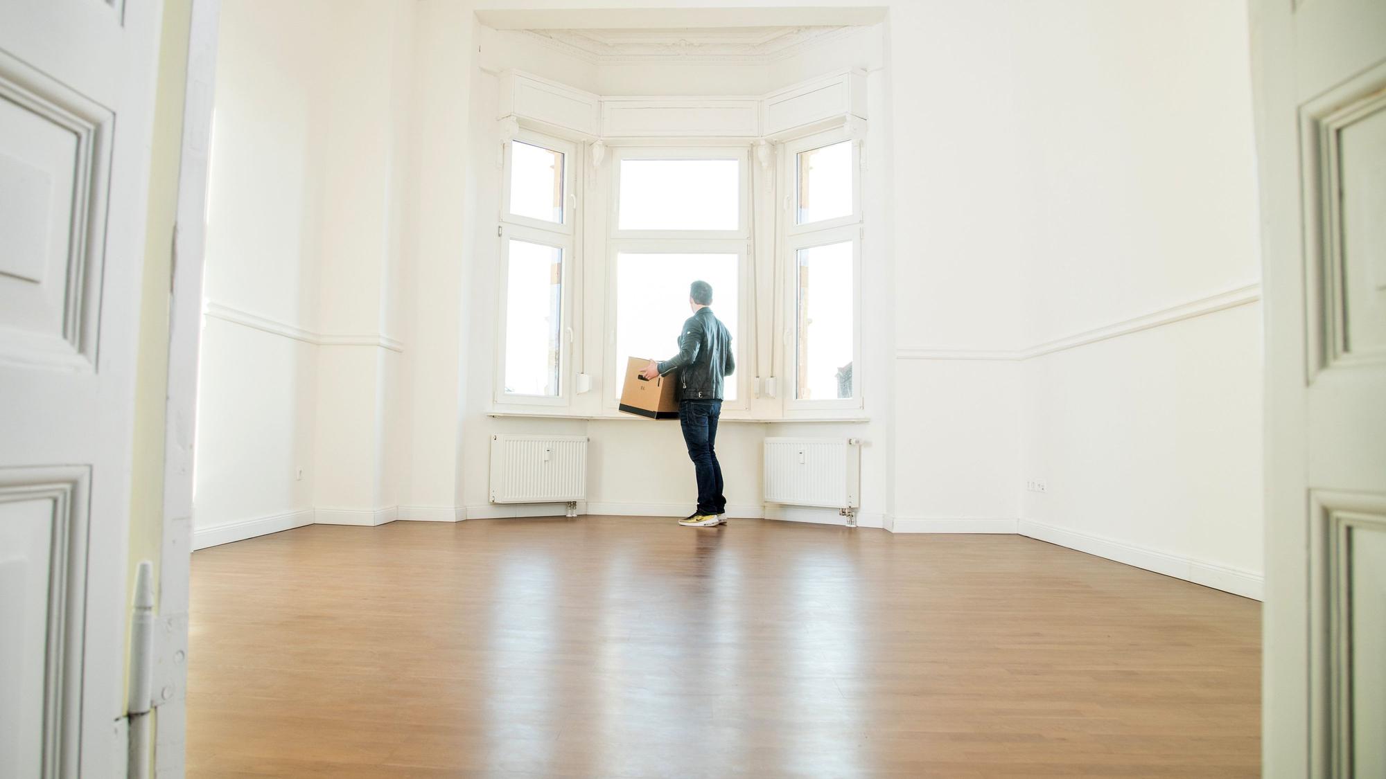 Das Symbolbild zeigte eine Person, die einen Karton in leere Wohnung trägt.