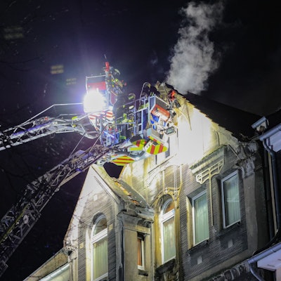 27.03.2025, Nordrhein-Westfalen, Leverkusen: Feuerwehrleute arbeiten mit zwei Drehleitern an einem Brand. Bei einem Wohnungsbrand in Leverkusen sind Menschen ums Leben gekommen. Vor Ort stellten die Feuerwehr dichten Rauch im dritten Obergeschoss des Hauses fest. Foto: Gianni Gattus/dpa +++ dpa-Bildfunk +++