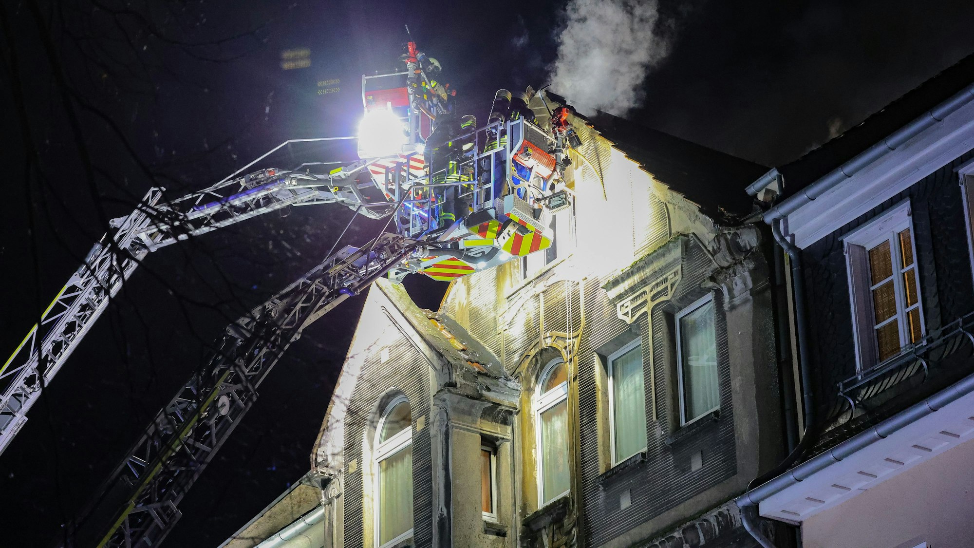 27.03.2025, Nordrhein-Westfalen, Leverkusen: Feuerwehrleute arbeiten mit zwei Drehleitern an einem Brand. Bei einem Wohnungsbrand in Leverkusen sind Menschen ums Leben gekommen. Vor Ort stellten die Feuerwehr dichten Rauch im dritten Obergeschoss des Hauses fest. Foto: Gianni Gattus/dpa +++ dpa-Bildfunk +++
