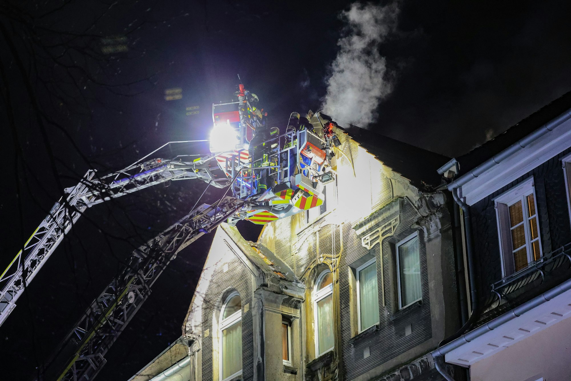 Feuerwehrleute arbeiten mit zwei Drehleitern an einem Brand.