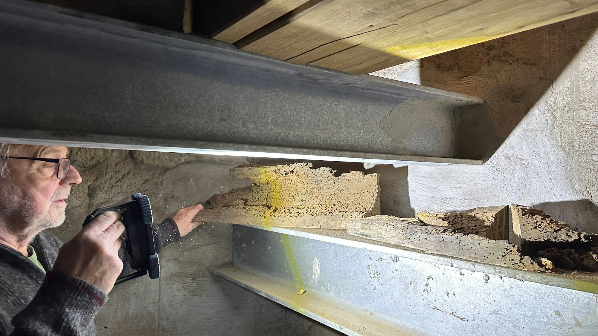 Manfred Bethge im Glockenturm von Sankt Servatius in Siegburg. Er leuchtet von Holzwürmern zerfressene Balkenstücke an, die ausgetauscht wurden. Stahlträger und neue Eichenbalken ersetzen sie jetzt.