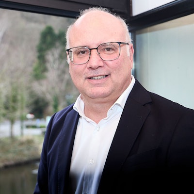 Ein Porträt des Bürgermeisters. Er steht vor einem Fenster mit Blick ins Grüne.