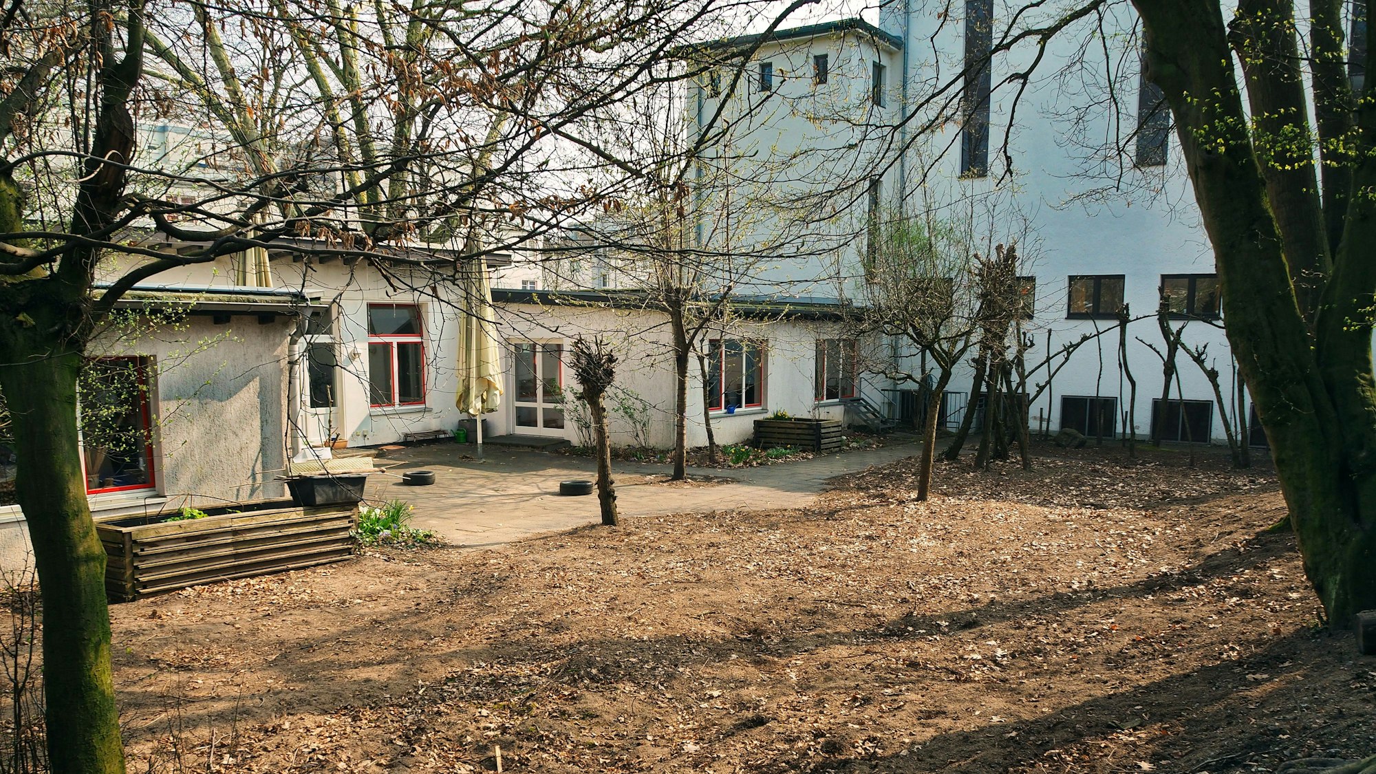 Ein Gebäude ist zu sehen, davor ist eine Freifläche mit Bäumen.