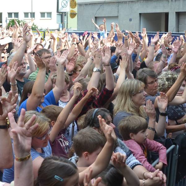 Frauen, Männer und Kinder drängen sich vor einer Bühne und klatschen im Takt zur Musik.